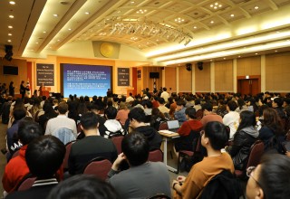 A large group of people in an auditorium are watching a presentation on internet peace.