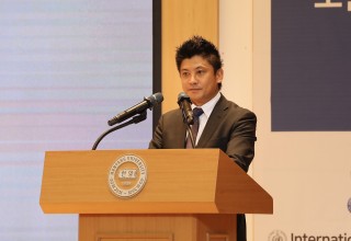 A man standing at a podium delivering a speech of congratulations.